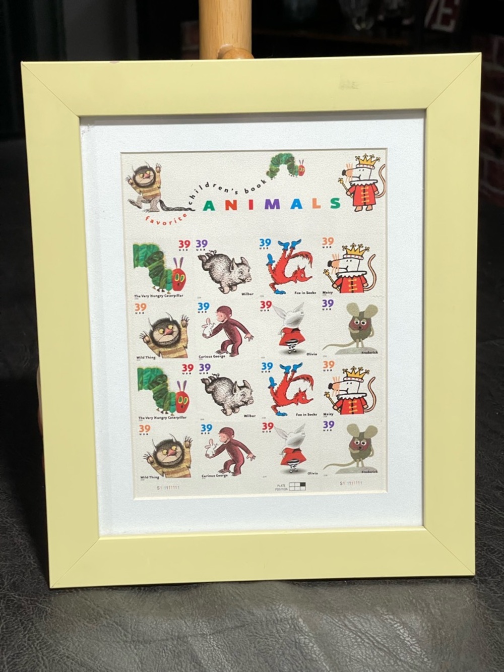 Framed postage stamps of children’s books. Frame soft yellow
